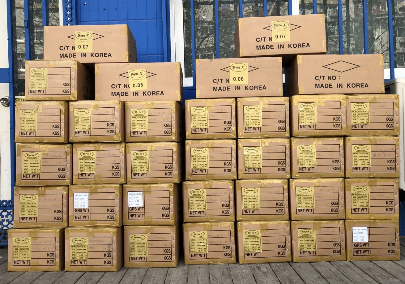 Shyne X Korean PBT lash fiber cartons stacked at the Qingdao store, marked C/T NO 0.05, 0.06 and 0.07, Made in Korea