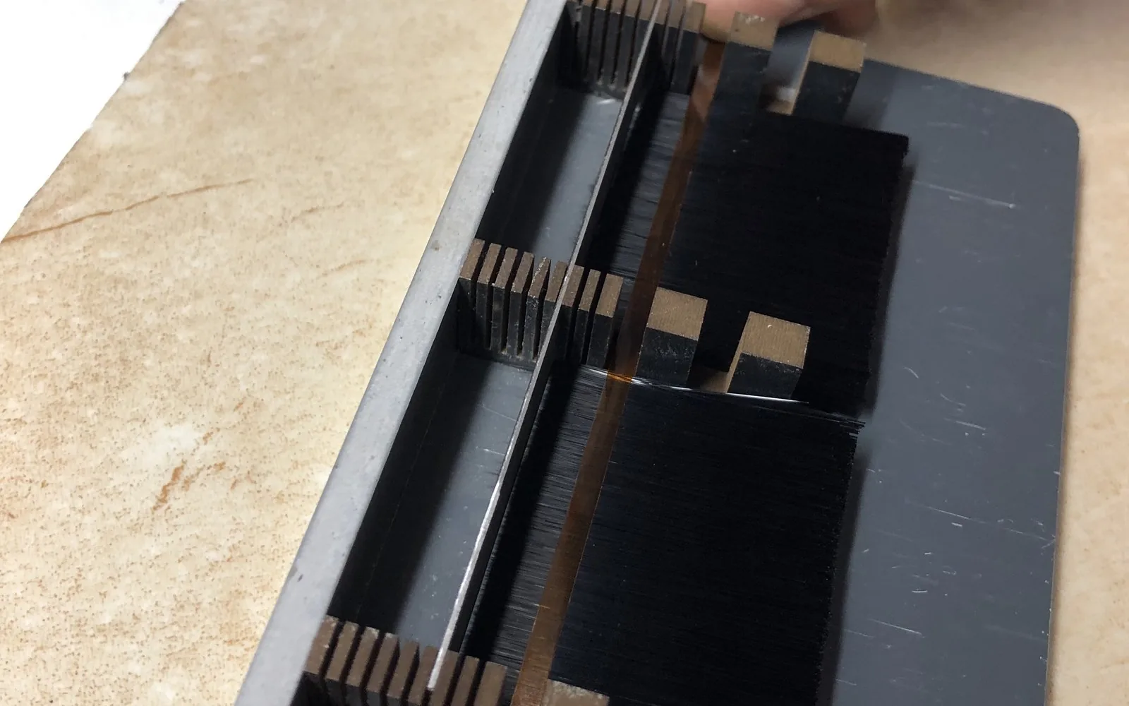 Lash fiber pressed flat in the aluminium taping plate, held under tape before it is cut